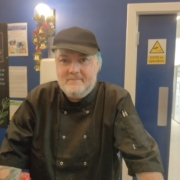 a smiling man with hat and apron